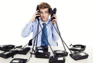 Young man in the office and answering several phones at the same