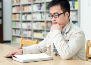 Handsome man sitting and reading in library